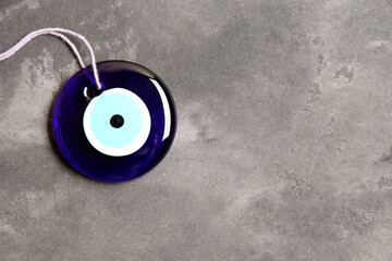 Evil eye amulet on grey table, top view. Space for text