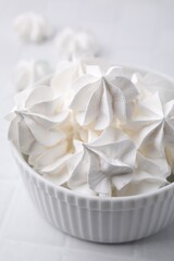 Delicious meringue cookies in bowl on white table, closeup