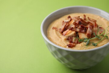 Delicious lentil soup with bacon and croutons on green background, closeup. Space for text
