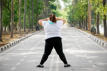 Rear view of young fat woman warming up before doing exercise in nature park
