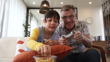 Grandfather and granddaughter together play console game, entertainment media. Old senior use...