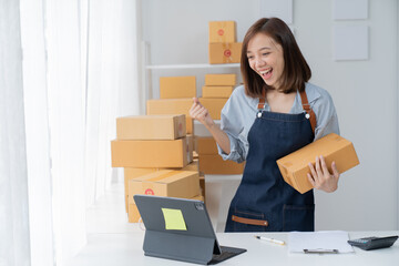 Delivery business. happy modern female checking order with laptop and using smartphone applications in the warehouse