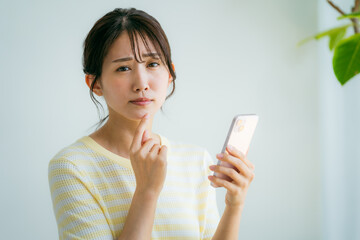 部屋でスマホを操作する女性