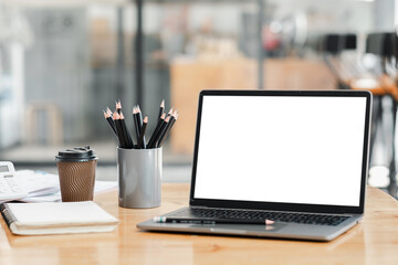 A laptop sits on a desk with a pencil holder and a cup of coffee. The laptop is open and the screen...