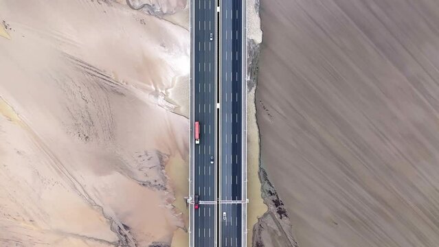 A vertical downward shot of the modern bridge and the mudflats beneath it.