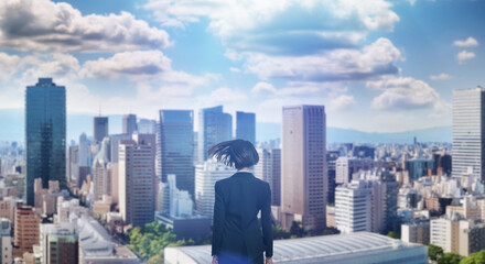 日本の街・都市・朝日を受けたオフィスビル群を前に佇み風を受けて髪をなびかせる会社員の女性の出勤　就職・ビジネス・はじまり・決意・目標・挑戦のイメージ