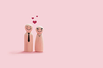 Happy wooden couple figures isolated on a pink background. The couple smiling and stand close together with hearts shape on their head - Powered by Adobe