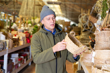 Caucasian man choosing wicker basket in decorative goods store.