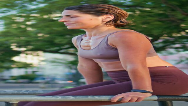Confident woman raising legs on parallel bars closeup. Vertical woman training