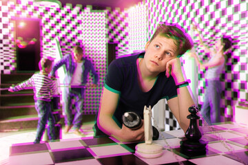 Portrait of thoughtful teenage boy trying to find solution of conundrum in quest room stylized...