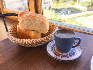 Homemade baguette and hot coffee on wooden table.