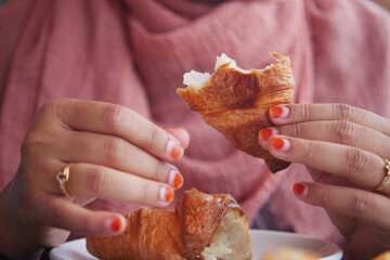 closeup of hand breaking a croissant bun 