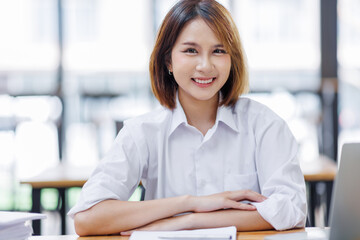 Happy asian business woman entrepreneur in office using laptop at work, smiling professional female company executive wearing suit working on computer at workplace.