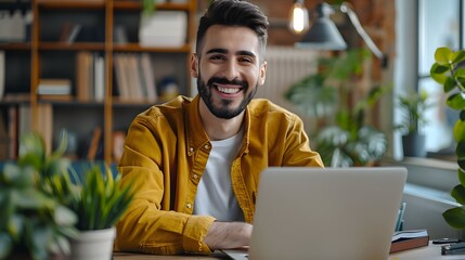 Obraz premium Cheerful Young Man Happily Working on Laptop in Cozy Office Environment