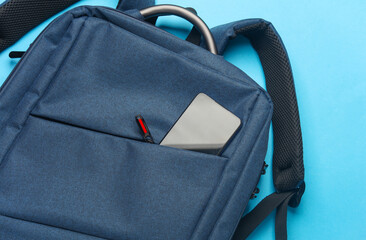 Backpack with smartphone on a blue background. Top view