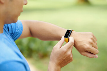 Close-up of a man in a blue shirt using his smartwatch to check heart rate during an outdoor activity