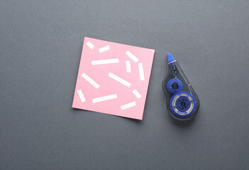 Tape corrector with memo paper on dark gray background. Top view