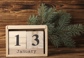 Wooden block calendar with date january 13 and pine tree on wooden background