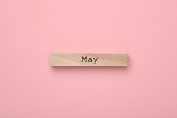 Wooden board with month May on pink background