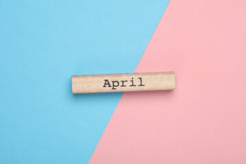 Wooden board with month April on blue pink background