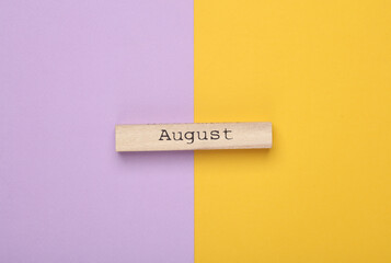 Wooden board with month Auguust on purple yellow background