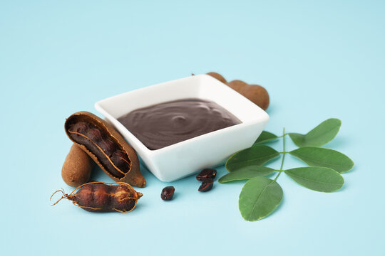 Bowl with tasty tamarind jam and fruits on blue background