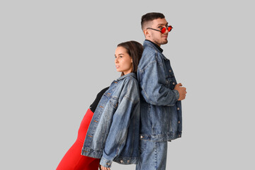 Stylish young couple in denim jackets on light background