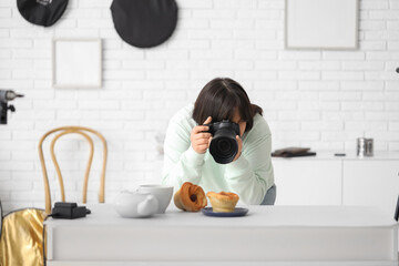 Female food photographer taking picture of cakes in studio