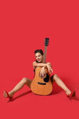 Portrait of beautiful pin-up woman with acoustic guitar on red background