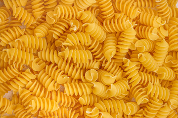 Delicious uncooked fusilli pasta as background