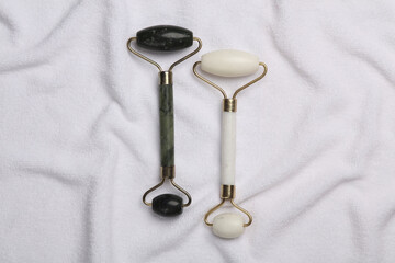 Jade facial rollers on white towel. Beauty concept. Top view