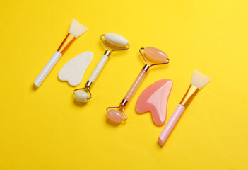Jade facial rollers and gua sha scrapers on yellow background. Beauty concept