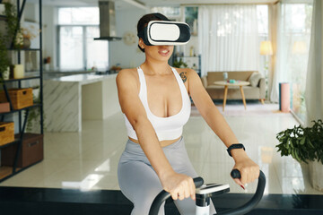 A woman exercising on a stationary bike wearing a VR headset in a contemporary living room, exploring virtual reality fitness