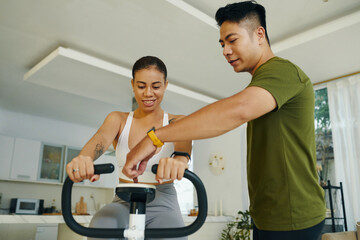 A man and woman adjusting the settings on an exercise bike together in a bright, modern living room focused on fitness