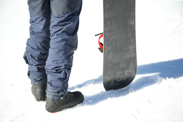 Legs of snowboarder on ski resort, back view