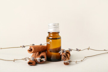 Bottle of essential oil, cinnamon sticks and dried lavender on white background