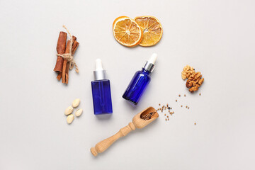 Bottles of essential oil with different ingredients on grey background