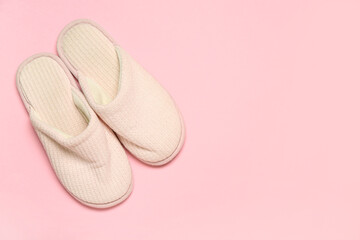 White soft slippers on pink background. Top view