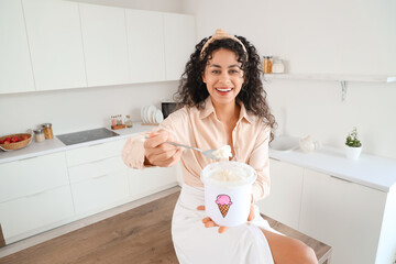 Happy young African-American woman with basket of ice cream in kitchen