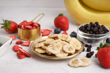 Tasty freeze-dried bananas and berries on white background