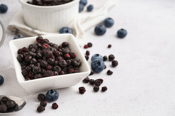 Bowl with freeze-dried blueberries on white background