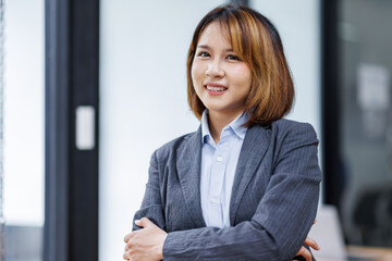Young Asian business woman smiling confidently while standing alone in a bright modern office
