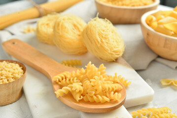 Different raw tasty pasta on light background, closeup