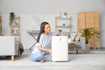 Modern humidifier and young woman on floor in living room