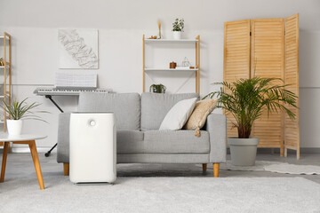 Modern humidifier near sofa in stylish living room