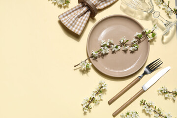 Beautiful table setting with blossoming branches on yellow background