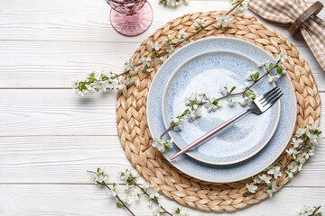 Beautiful table setting with blossoming branches on white wooden background