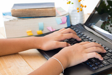 student girl type computer and read a book dictionary english for study on table