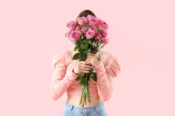 Young woman with roses on pink background