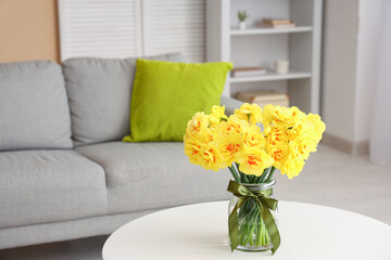 Vase with daffodil flowers on coffee table in living room